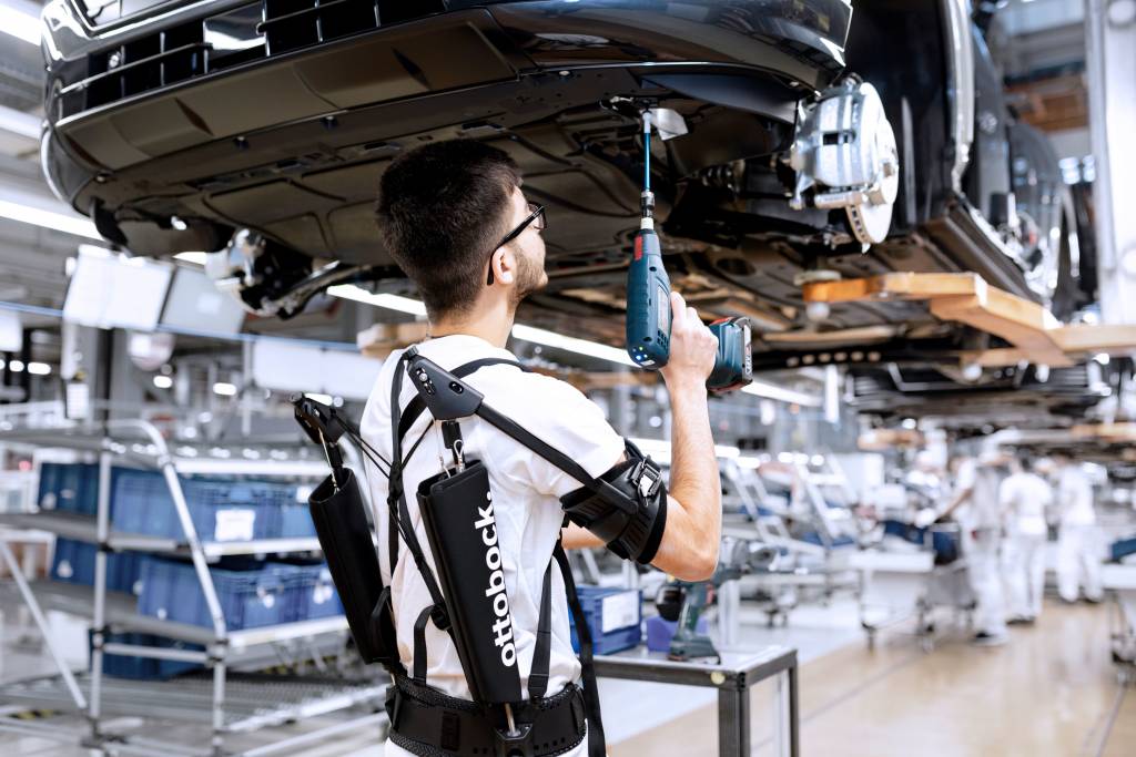 Audi is testing exoskeletons for performing overhead tasks. These external support structures help employees by protecting their joints and tiring their muscles less quickly. Employees in the assembly are testing the exoskeletons while screwing the underb