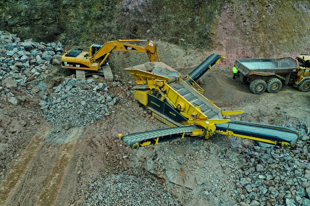 In mining, the Caterpillar CAT 325C hydraulic crawler excavator rocks into the Keestrack mobile crushing and sorting plant in a quarry. Construction machinery concept. MÃ¡ny - Hungary 01.04.2021.