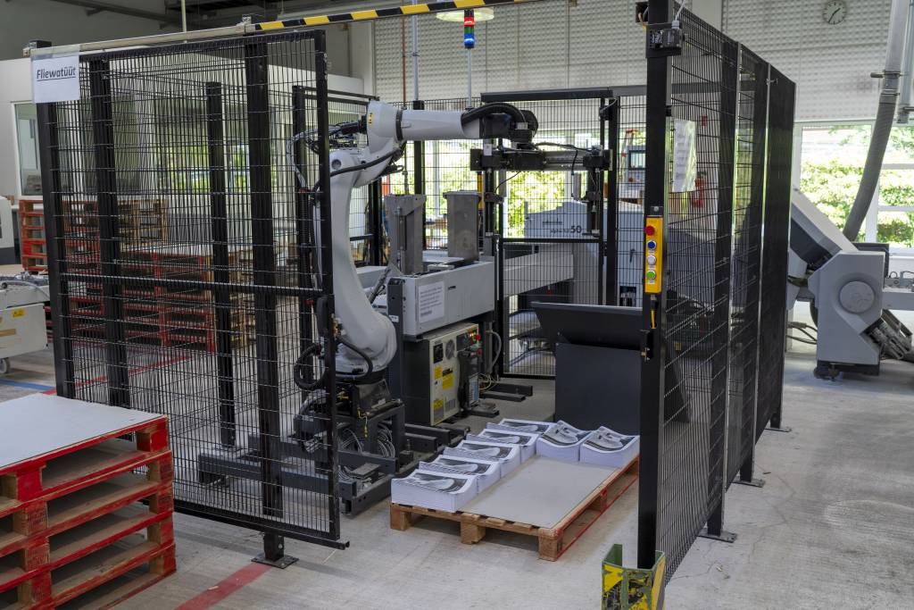 Der Pick&Place-Roboter P-Stacke nimmt bei Heidelberger Druckmaschinen Stapel gefalzter Papierbögen von der Falzmaschine auf und legt sie auf einer Palette ab.